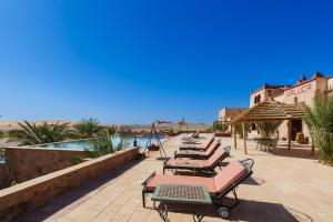 a row of lounge chairs and tables on a patio at Hotel Riad Xaluca in Merzouga