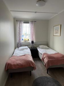 two twin beds in a room with a window at Bryggans Vandrarhem in Västervik