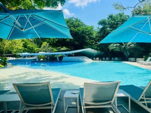 a swimming pool with chairs and blue umbrellas at Carolina Peach, Studio unit E-6H Tambuli Resort! in Maribago