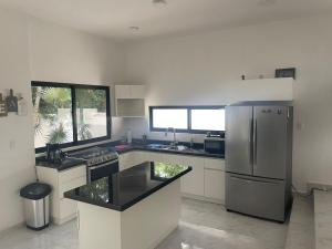 a kitchen with a stainless steel refrigerator and a window at Casa Maya in Puerto Morelos