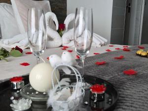 a table topped with two wine glasses and red roses at Au bonheur des ruelles in Monpazier