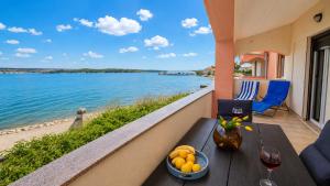 a table with a bowl of fruit on a balcony overlooking the water at Dana Apartments - Seafront Pašman in Pašman