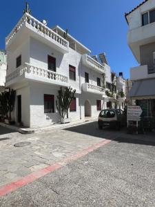 a white building with a car parked in front of it at Almyra Summer Homes in Ierapetra
