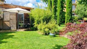 a yard with an umbrella and some bushes and a house at Tiny House de Charme & Oasis Privée in Toulouse