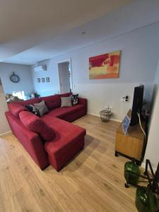 a living room with a red couch and a flat screen tv at Casa da Padaria in Folgosa