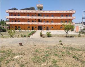 a large orange building with a lot of windows at The Prem Vatika Homestay Maihar in Maihar