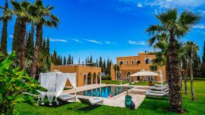 a house with a swimming pool and palm trees at Luxury villa in Azib Oulad Lâdem