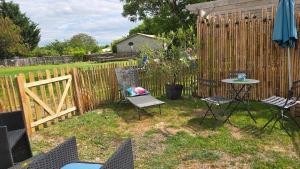 a backyard with chairs and a table and a fence at "Un aparté bohême" le STUDIO in Puyravault +4 photos