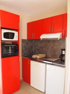 a kitchen with red cabinets and a microwave at Appartement Soleil d'Oc 5 in Cazaubon