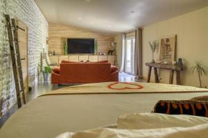 a bedroom with a bed and a couch and a television at SUITE TESORO climatisée avec piscine spa hammam et jardin avec piscine in Saint-Martial-sur-Né