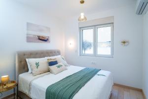 a white bedroom with a bed with a window at Apartments with Pool 5 Min Walk to Beach in Igalo +37 photos