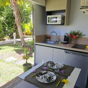 a kitchen with a counter top with a sink and a table at Ti Pipirit in Saint-François