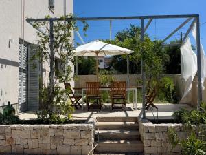 a patio with a table and chairs and an umbrella at Supetar Cypress House - near the beach in Supetar