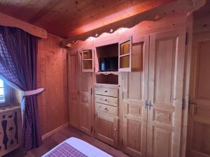 a bedroom with wood paneling and a cabinet and a bed at La chambre Chez Marion 2 personnes in Notre-Dame-de-Bellecombe