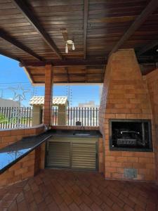 an outdoor kitchen with a brick fireplace on a patio at Ótima casa 3 quartos, piscina, bem localizada in Foz do Iguaçu