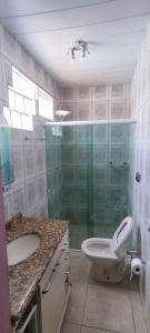 a bathroom with a toilet and a sink and a shower at Ótima casa 3 quartos, piscina, bem localizada in Foz do Iguaçu