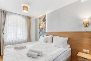 a bedroom with a white bed with two towels on it at Dokia Boutique in Gura Humorului