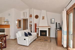 a living room with a white couch and a fireplace at Stazzo La Chèa in Nuragheddu