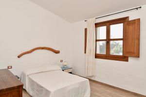 a white bedroom with a bed and a window at Stazzo La Chèa in Nuragheddu