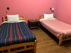 two beds in a room with pink walls at Imperio Carlos V in Oruro