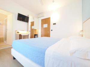 a white bedroom with a large bed with blue sheets at Hotel Angelo in Caorle