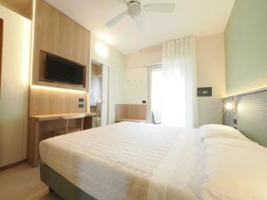 a bedroom with a large white bed with a flat screen tv at Hotel Angelo in Caorle