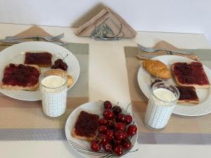 a table with plates of bread and cherries and glasses of milk at K & A Studios 2 in Nydri