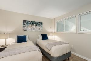 two beds in a room with white walls and windows at Glacier Lodge in Whistler