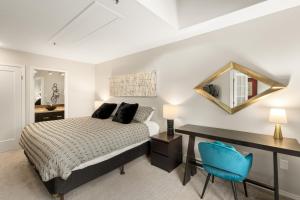 a bedroom with a bed and a desk and a mirror at Glacier Lodge in Whistler