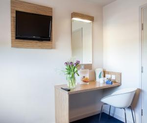 a room with a vase of flowers on a counter with a mirror at Redwings Lodge Wolverhampton Central in Wolverhampton