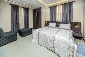 a bedroom with a large bed and two chairs at Davina's Villa in Kumasi