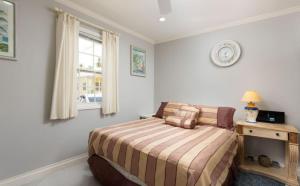 a bedroom with a bed and a clock on the wall at The Little White Cottage in Saint Peter