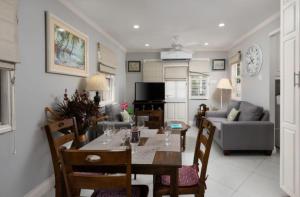 a dining room and living room with a table and chairs at The Little White Cottage in Saint Peter