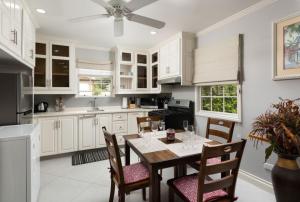 a kitchen with white cabinets and a table and chairs at The Little White Cottage in Saint Peter
