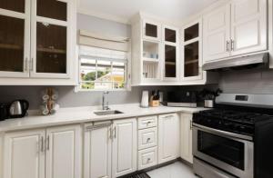 a white kitchen with white cabinets and a stove at The Little White Cottage in Saint Peter +1 photo