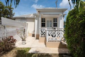 a small white house with a white fence at The Little White Cottage in Saint Peter