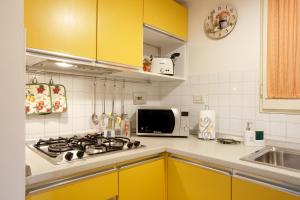 una cucina con armadi gialli, piano cottura e forno a microonde di Appartamento La Casina a Pistoia