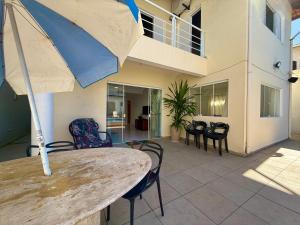 a patio with a table and chairs and an umbrella at Casa virgínia enseada in Guarujá