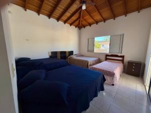 a bedroom with three beds and a window at Casa virgínia enseada in Guarujá +48 photos