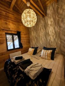 a bedroom with a large bed with a chandelier at Le Chalet Cocon et Jacuzzi in La Petite-Pierre