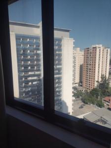 a window view of a city with tall buildings at MN Gotado Hotel Flat Guarulhos Aeroporto in Guarulhos