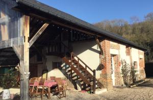 a building with chairs and a staircase in front of it at Au Paddock du Bec in Le Bec-Hellouin