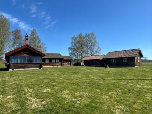a house with a grass field in front of it at Lake Lodge Rönnäs in Leksand