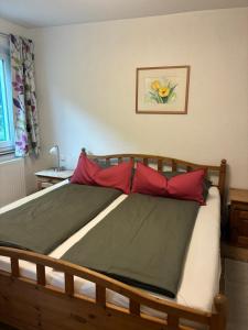 a bedroom with a wooden bed with red pillows at Garten Apartment Diwoky in Sankt Gilgen