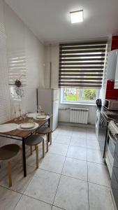 a kitchen with a table and chairs and a large window at Central Square Apartment in Ternopil
