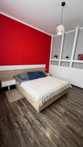 a bedroom with a bed and a red wall at Central Square Apartment in Ternopil