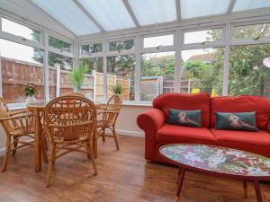 a living room with a red couch and a table at 31 Llys Ogwen in Prestatyn