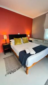 a bedroom with a large bed with a red wall at The Muizenberg Muse in Muizenberg