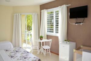 um quarto com uma cama, uma mesa e uma janela em Pousada Recanto dos Feijós em Florianópolis
