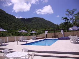 uma piscina com mesas e cadeiras e uma mesa e cadeiras em Pousada Recanto dos Feijós em Florianópolis
